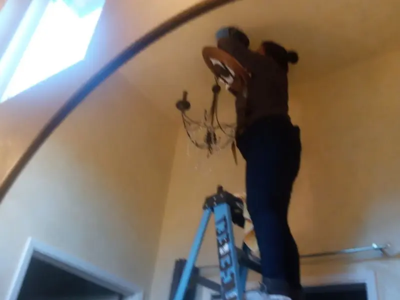 Electrician installing a chandelier in a Helena-West Helena residence